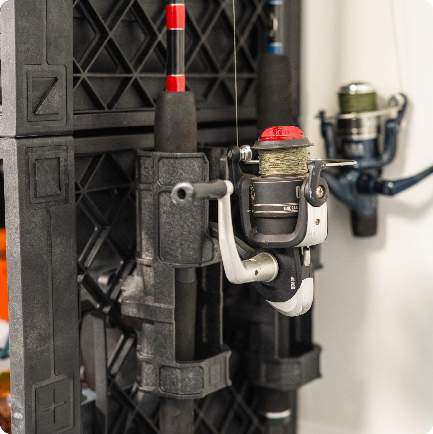 Black UbeCube fishing crate with a side-mounted Fishing Pole Holder securing a fishing rod and spinning reel.