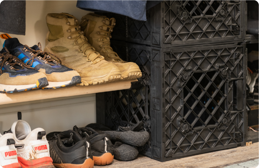 Black UbeCube crate shoe storage setup with boots and sneakers organized on closed rods that are connected to the RodSnaps, in a closet or entryway space.