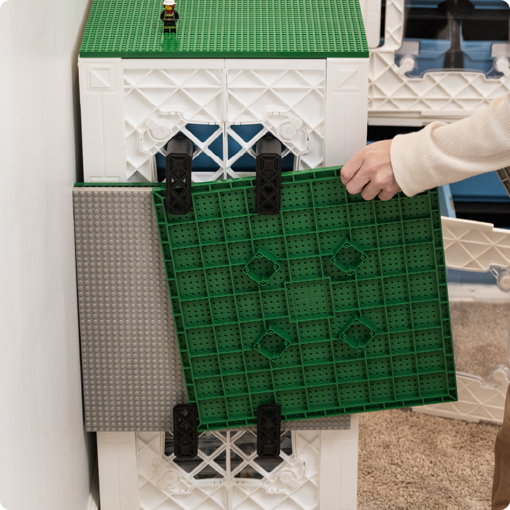 Green CratePlay build plate stored on the side of white UbeCube crates using black CrateHooks.