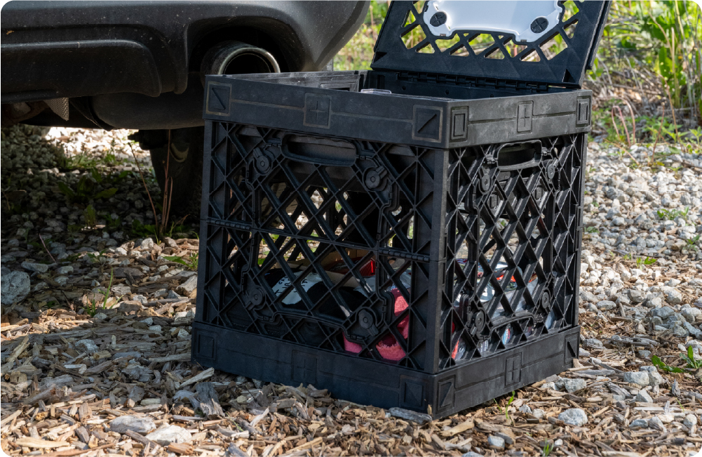 Black UbeCube crate filled with emergency supplies and stored outdoors near the back of a vehicle.