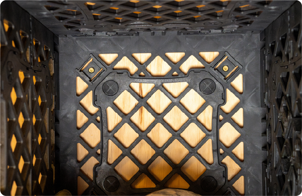 Interior view of a black UbeCube crate secured to a wooden wall using Screw Clips mounted through the crate’s open grid