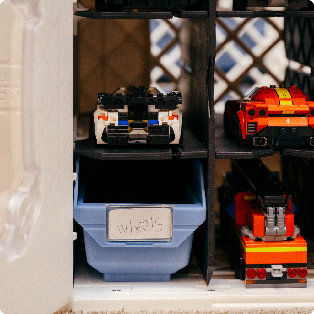 White UbeCube CratePlay setup with CrateRails supporting CrateDividers, LEGO-compatible vehicles, and a labeled blue Grabinet Bin.