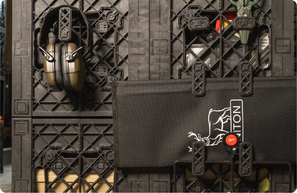Black UbeCube crate wall setup with quarter-turn hook and plier holder accessories holding ear protection, tools, and a black gear pouch.