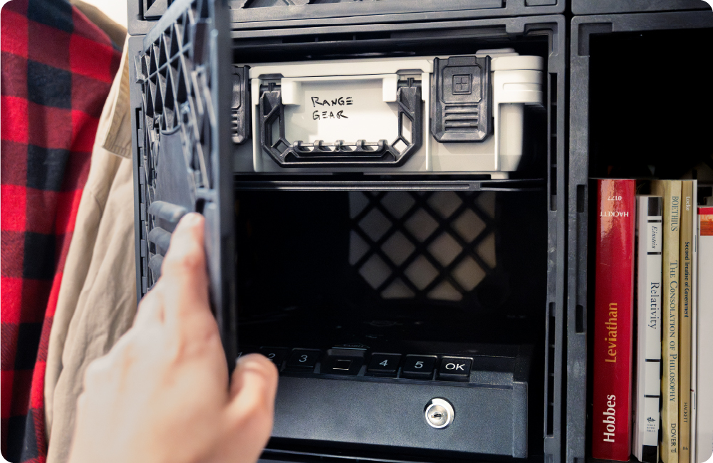 Open black UbeCube crate cabinet with a labeled Range Gear BaseBox stored above a keypad safe and books.