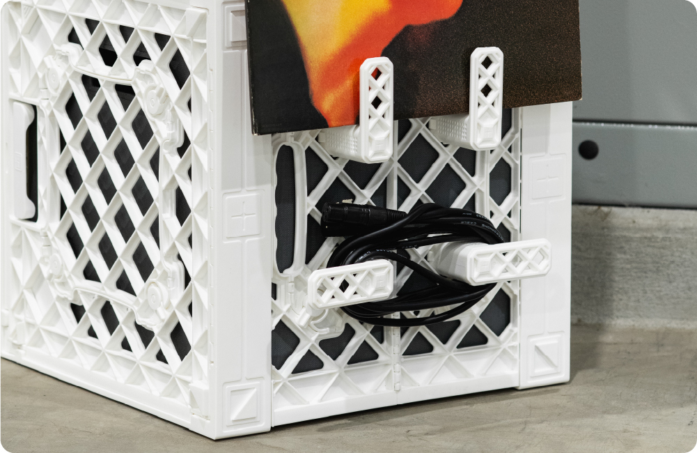 White UbeCube crate with white quarter-turn CrateHooks holding a vinyl record and coiled audio cables on the side grid.