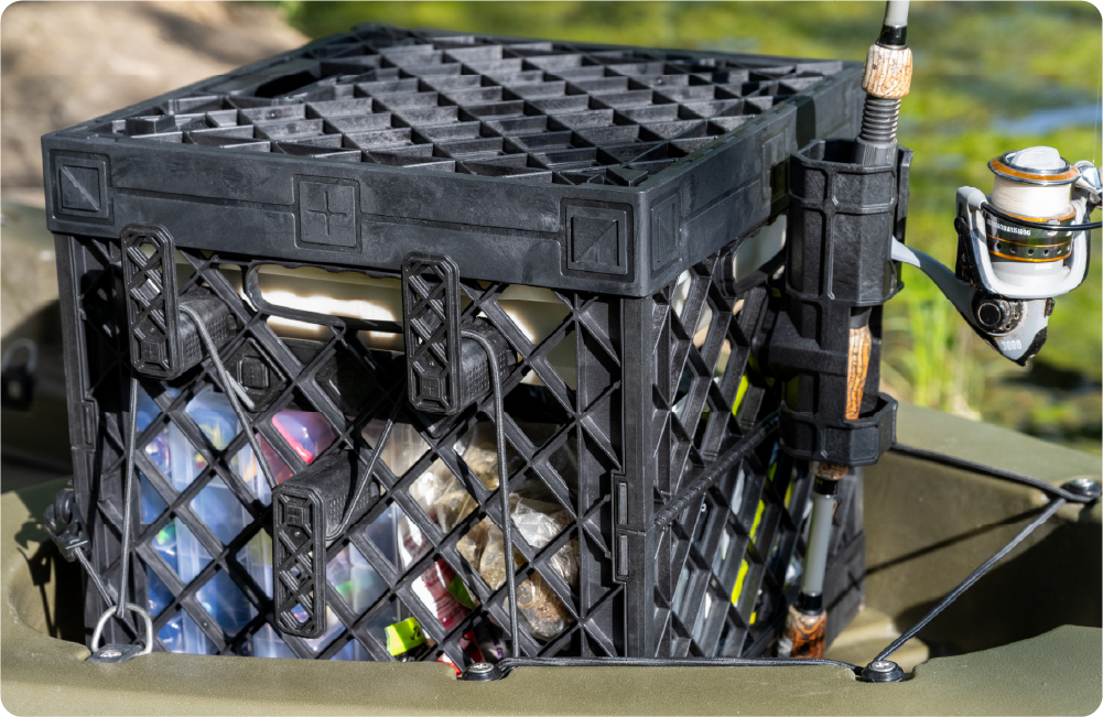 Black UbeCube fishing crate mounted on a kayak with tackle stored inside and a fishing rod held in a side-mounted fishing pole holder.