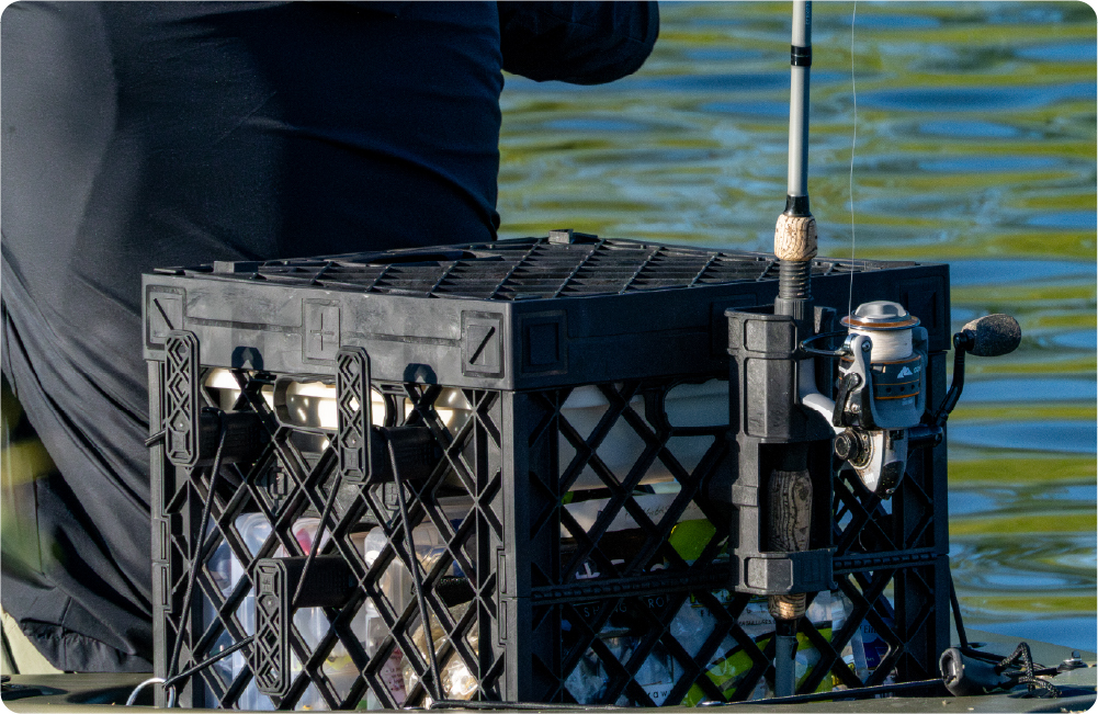 Black UbeCube fishing crate on a kayak with a side-mounted fishing pole holder securing a fishing rod.
