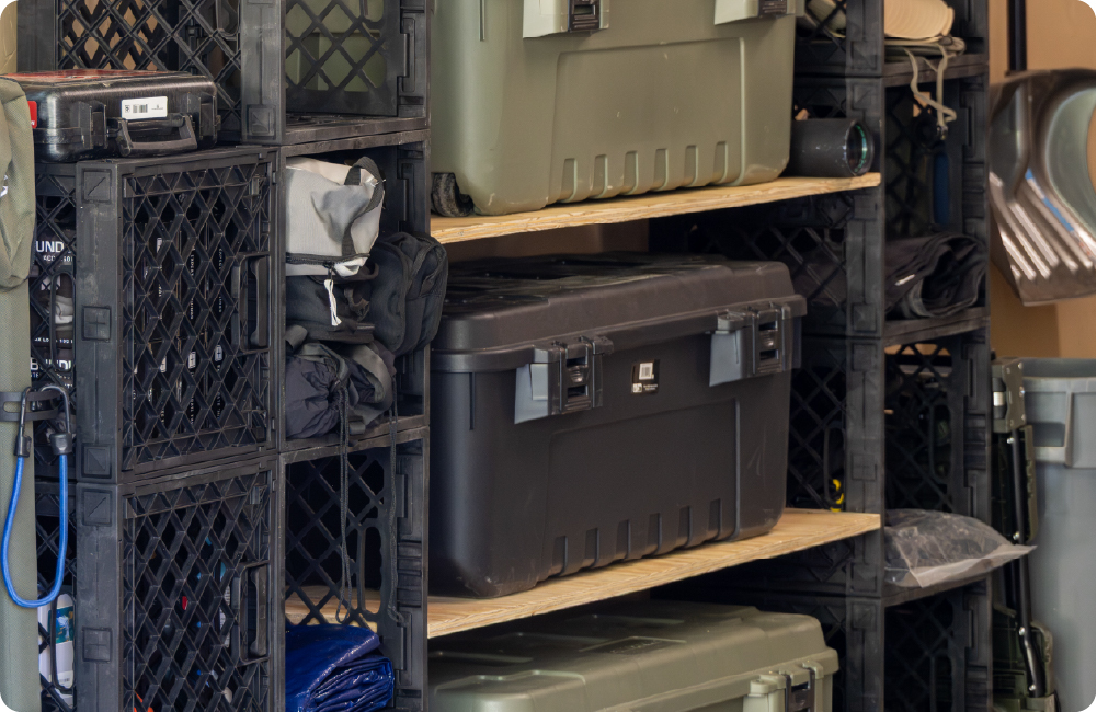 Garage storage setup with black UbeCube crate towers, wooden shelves, and large gear boxes organized inside.
