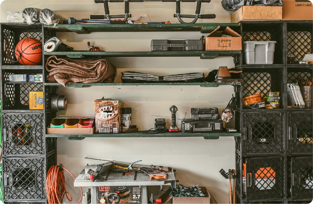 Garage wall storage setup with black UbeCube crate towers, open shelves, tools, supplies, basketball, cords, and workshop gear organized around a central work area.