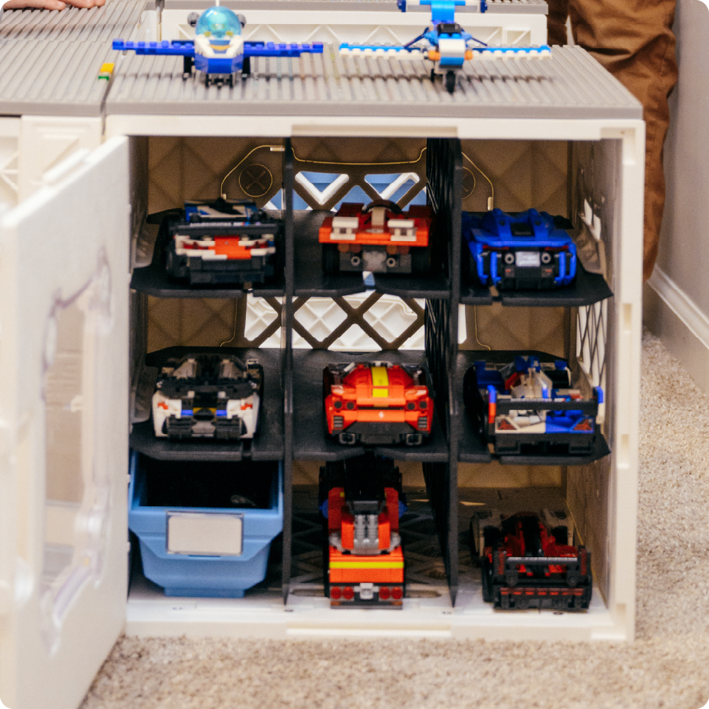 White UbeCube CratePlay setup with CrateDividers creating shelves for LEGO-compatible vehicles and a blue Grabinet Bin stored below.