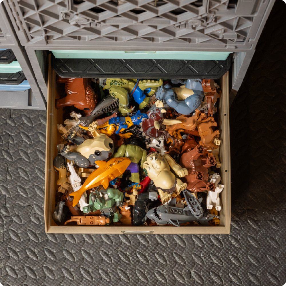 Grabinet Bin filled with toy animal figures and small play pieces inside a gray UbeCube CratePlay storage setup.