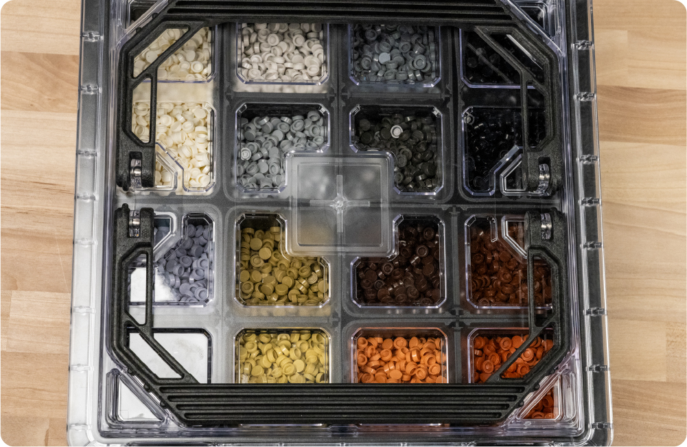 Top-down view of a clear-lid BaseBox™ used as a Pixel Panel storage case filled with sorted neutral-colored studs.