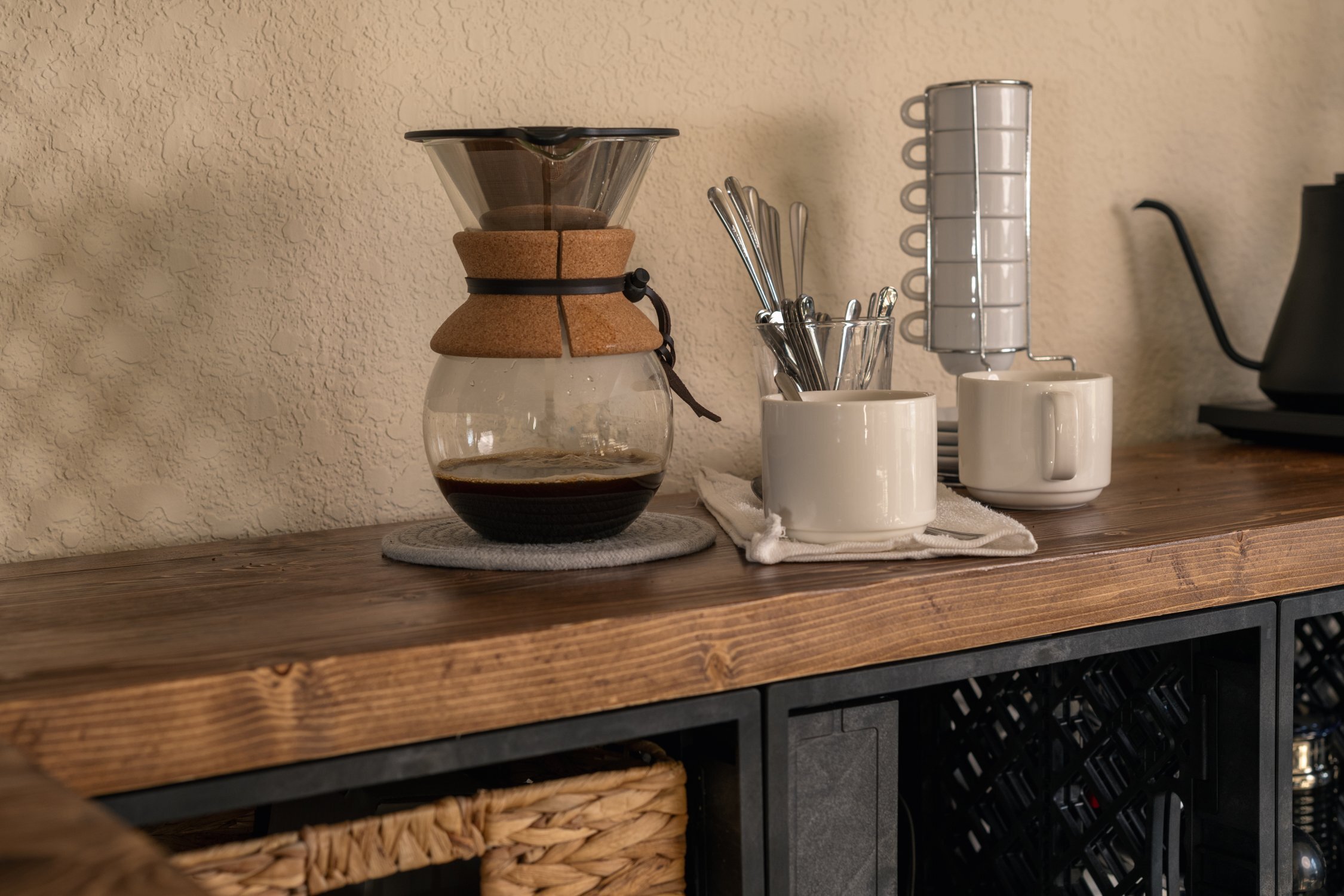 Coffee and pour-over setup on wood surface above crate storage.
