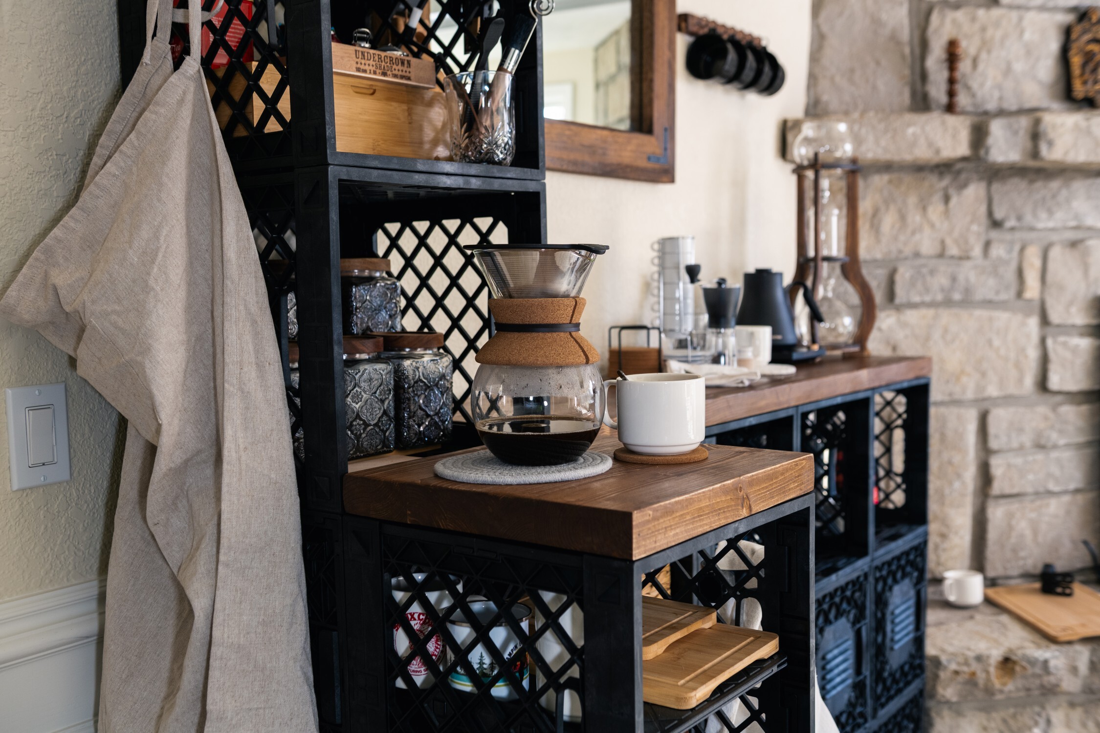 Coffee station positioned near fireplace with tea, mugs, and countertop space.