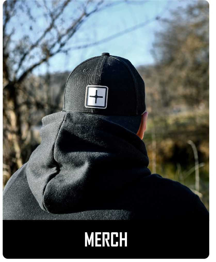 Black CratePlay™ cap with square logo patch worn outdoors near a lake or wooded area.