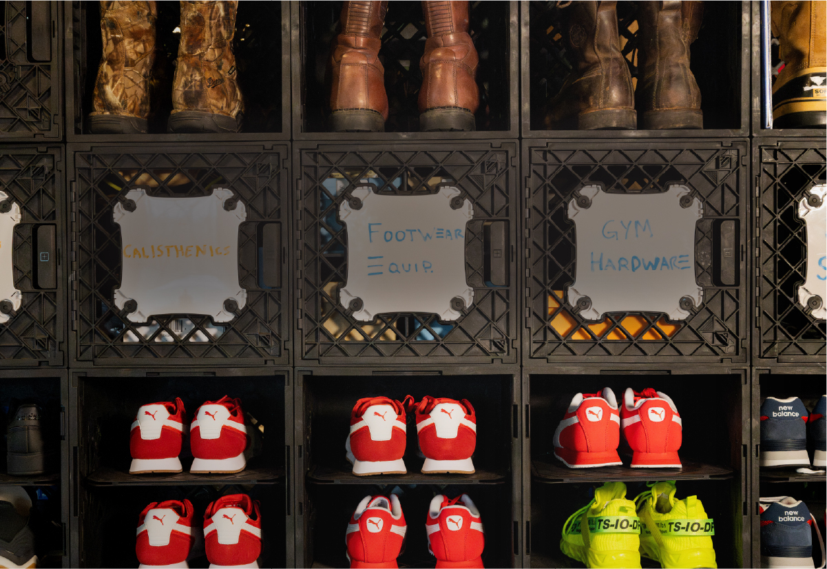 Black modular crate storage wall with shoes, whiteboard labels, and organized gym and footwear gear.