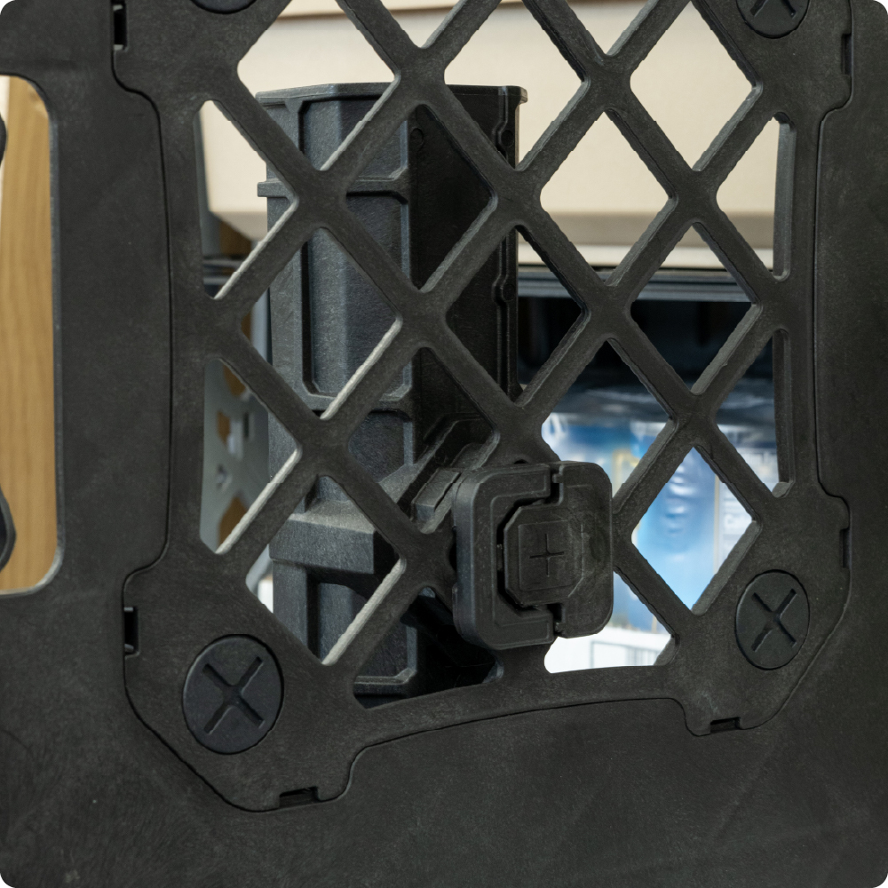 Close-up of a black D-Ring Connector quarter-turned through the side grid of a black UbeCube crate to hold a fishing pole holder.