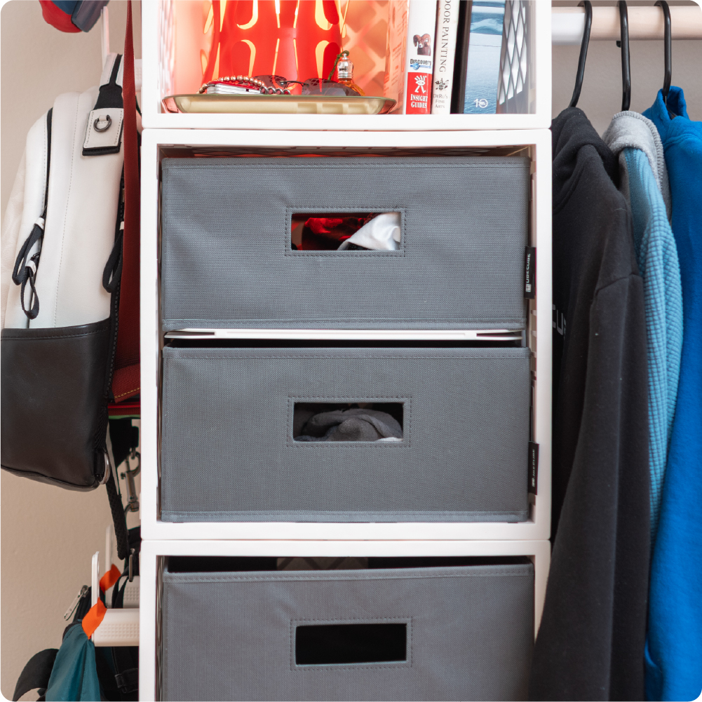 White UbeCube CrateCloset setup with stacked gray half-size Fabric Bins storing folded clothing beside hanging garments.