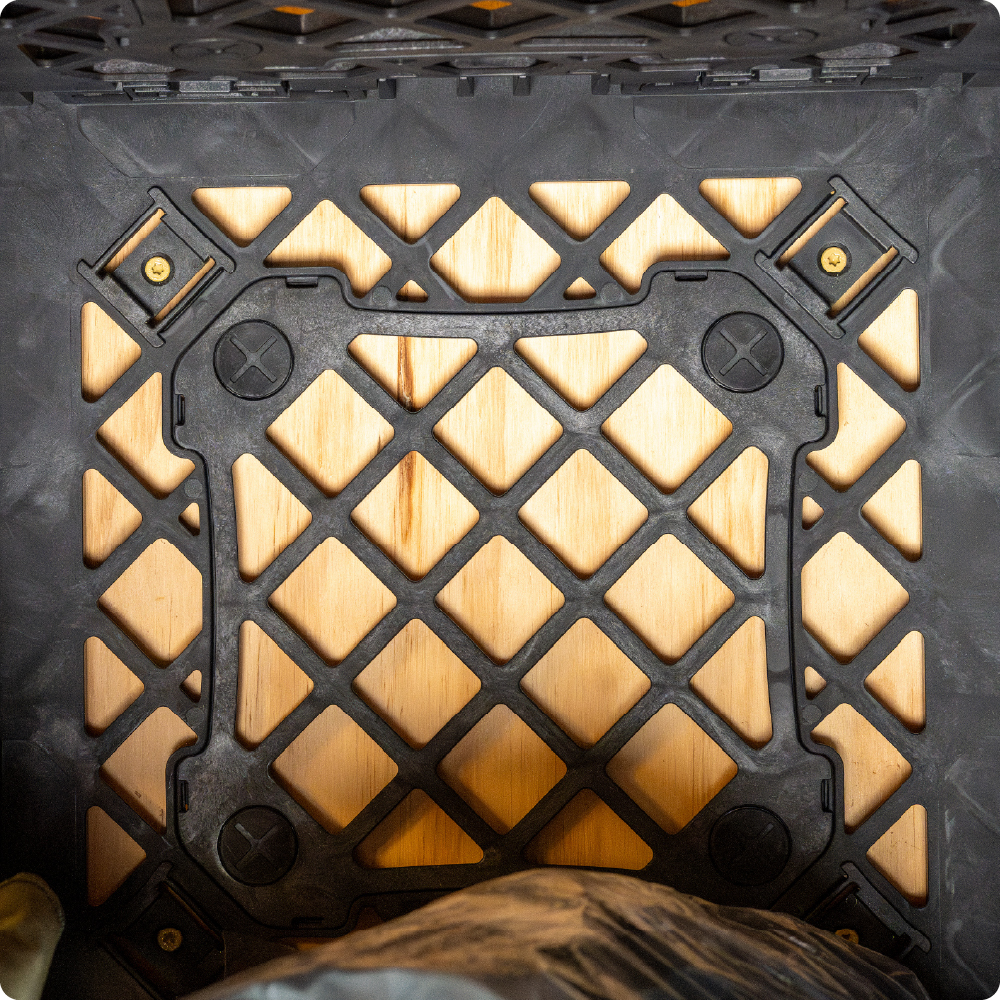 Interior view of a black UbeCube crate secured to a wooden wall using Screw Clips mounted through the crate’s open grid