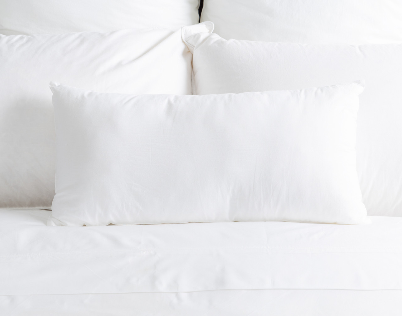 Boudoir Pillow Insert sitting on a solid white bed.