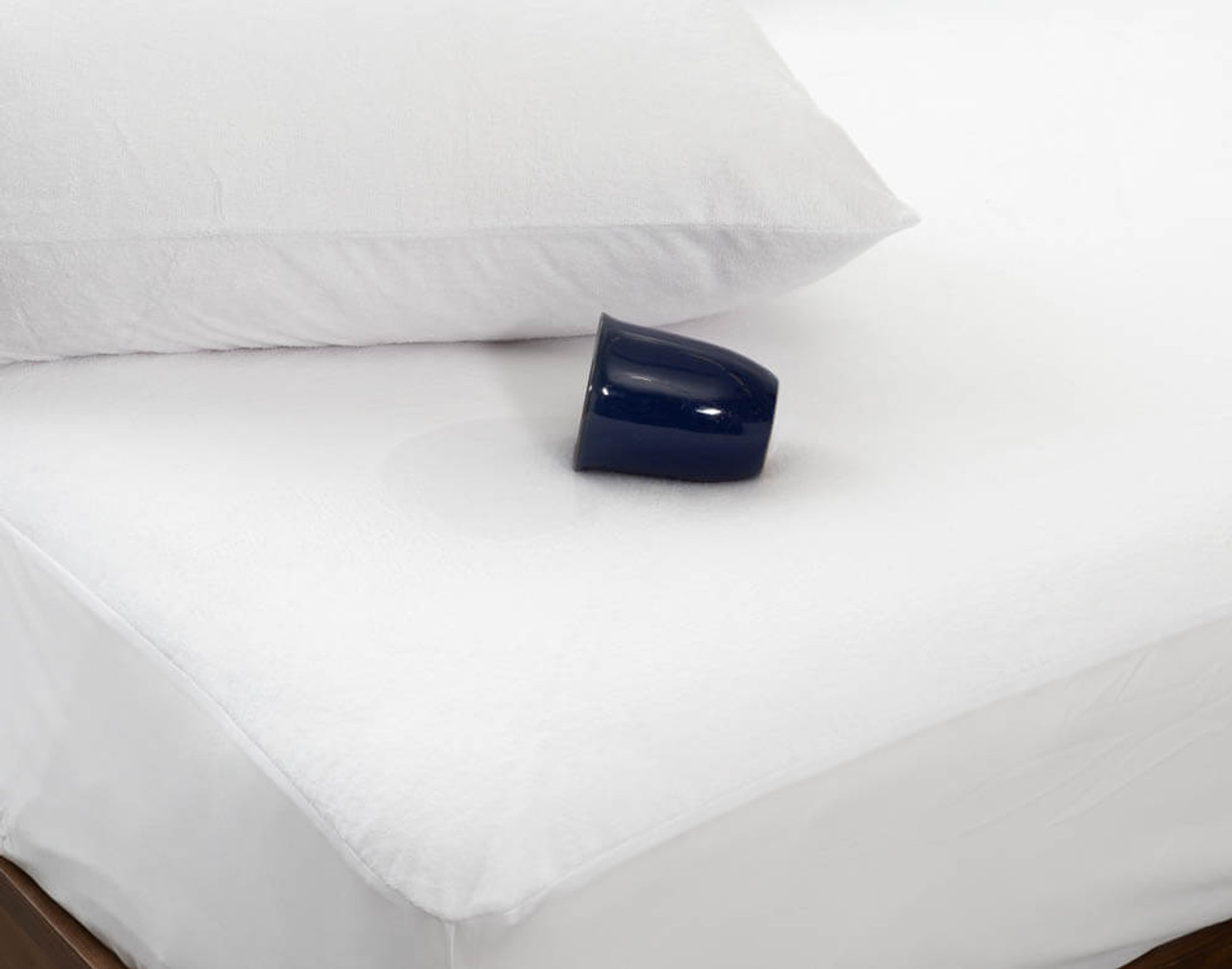 SureRest WaterprVue inclinée de notre protège-matelas imperméable SureRest avec une tasse tombée sur le côté au-dessus du protège-matelas.oof Mattress Protector