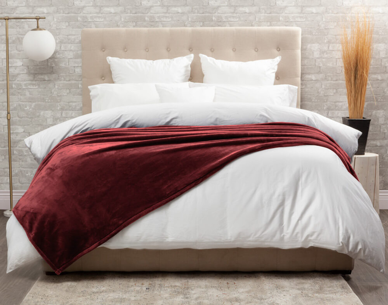 Our Rhubarb Cashmere Touch Fleece Blanket in Rhubarb dressed over a comfortable white bed.