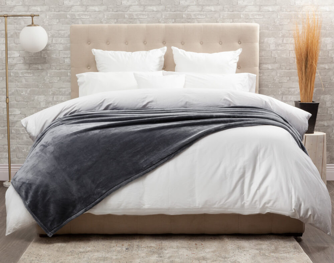 Our Grey Cashmere Touch Fleece Blanket in Volcanic Grey dressed over a comfortable white bed.