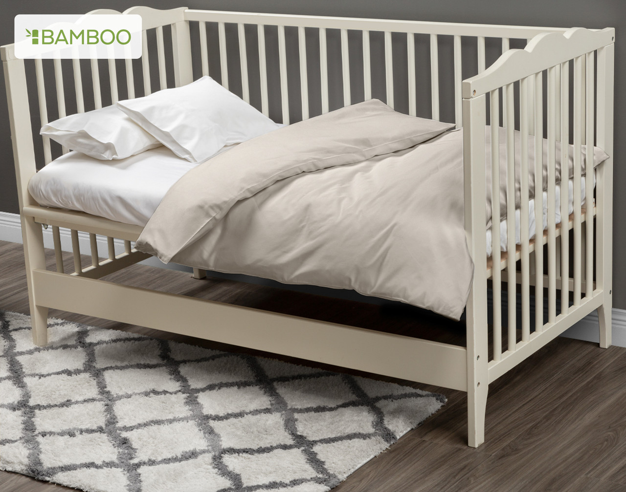 Notre housse de couette pour lit d'enfant Bamboo Cotton en Driftwood habille un petit matelas blanc dans un lit d'enfant blanc crème.