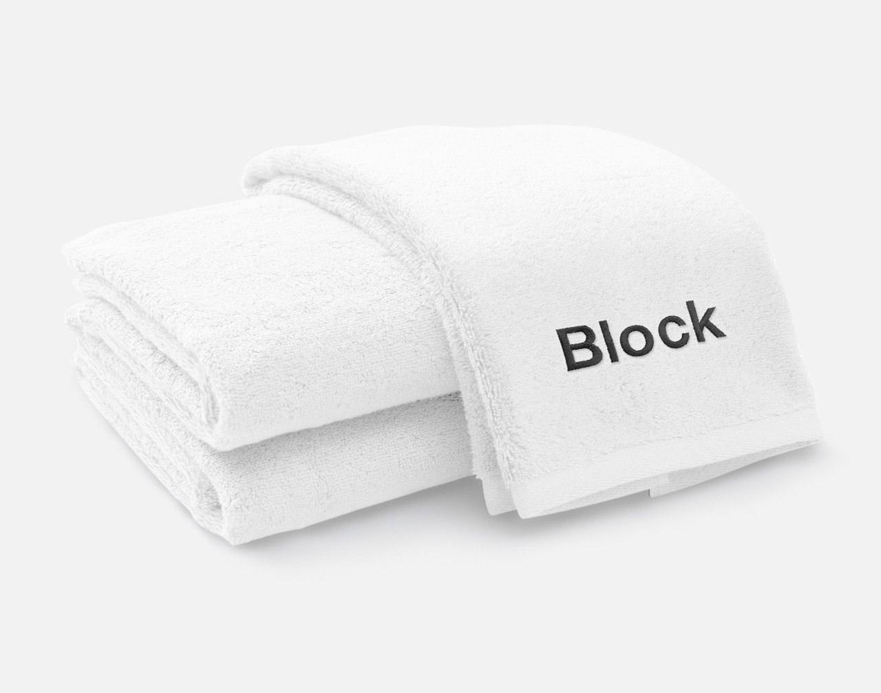 Vue pliée de notre serviette brodée personnalisée ensemble en blanc, avec la police Block brodée en blanc noir le long du bord inférieur.