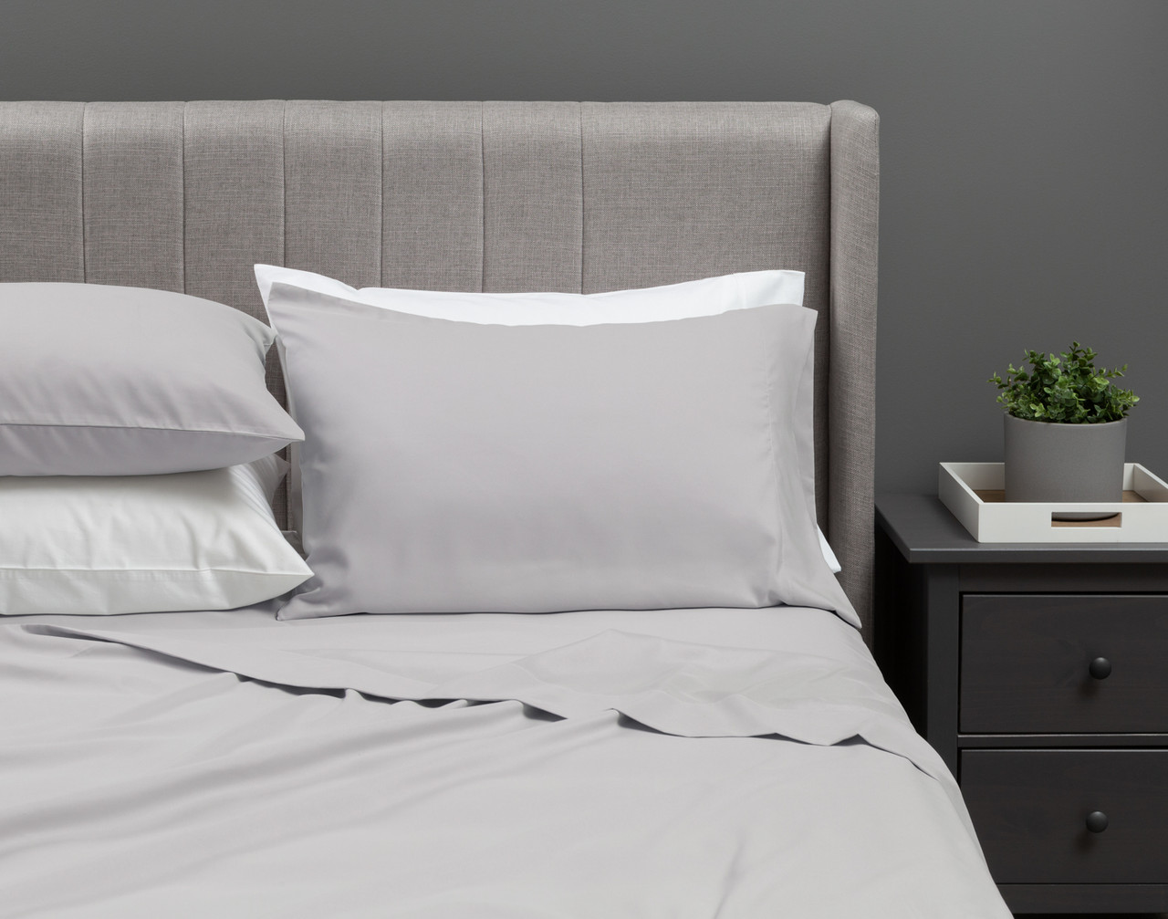 Our Recycled Microfiber Sheet Set in Steel dressed over an undecorated bed in a neutral grey bedroom.