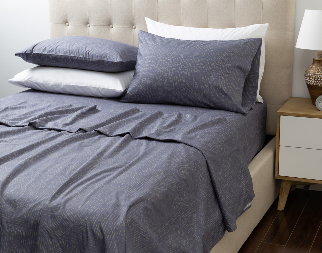 Our Recycled Microfiber Sheet Set in Brooks dressed over an undecorated bed in a neutral bedroom.