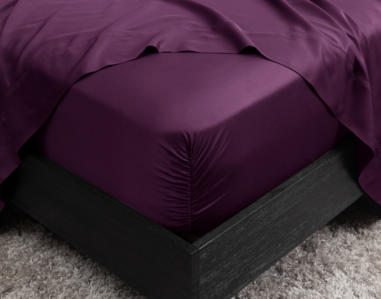 Gros plan sur le coin de notre BeechBliss TENCEL™ Modal Fitted drap en Plum qui s'adapte parfaitement à un matelas avec un drap plat drapé sur le dessus.