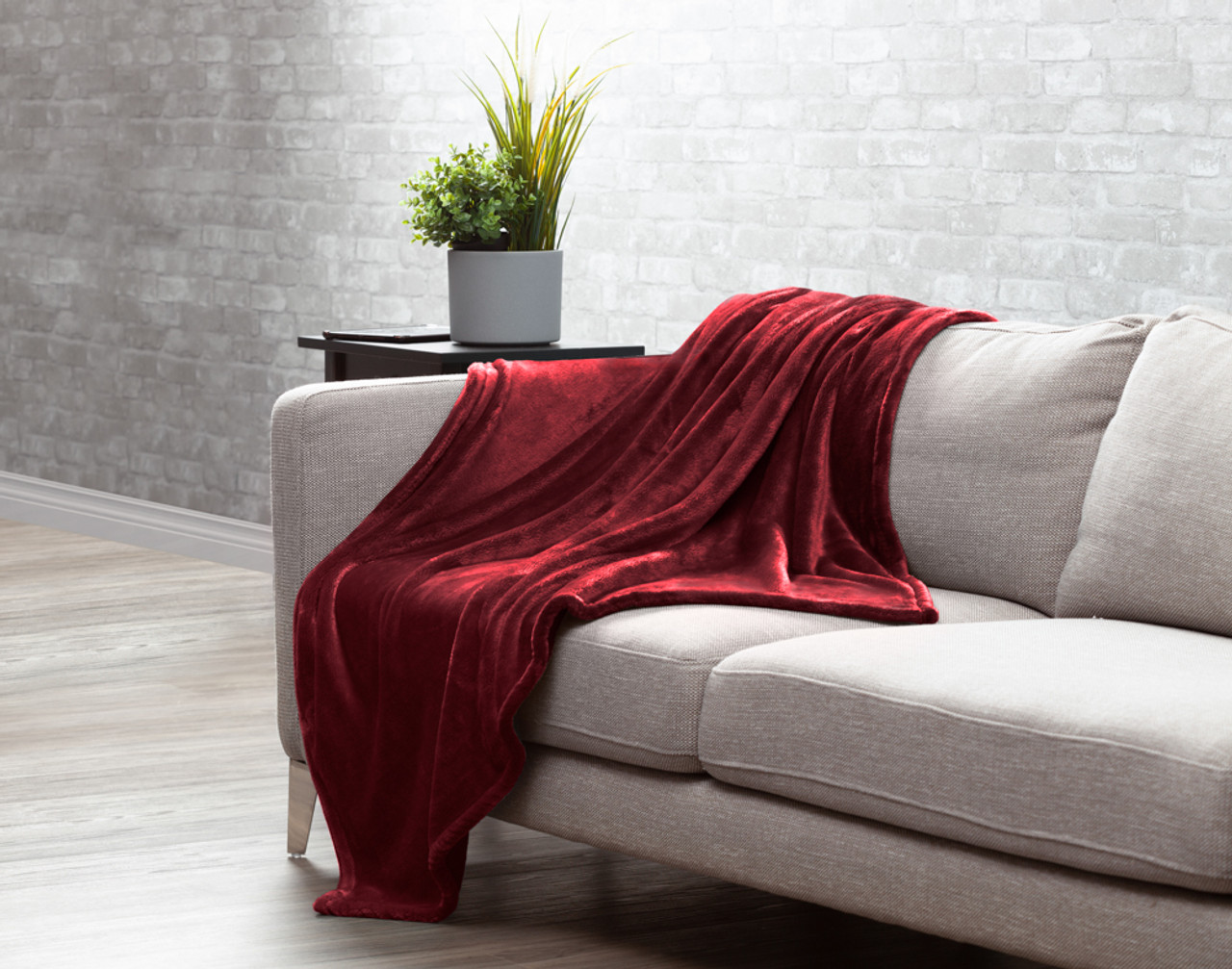 Our Velvet Plush Throw in Merlot draped over a beige couch in a white living room.