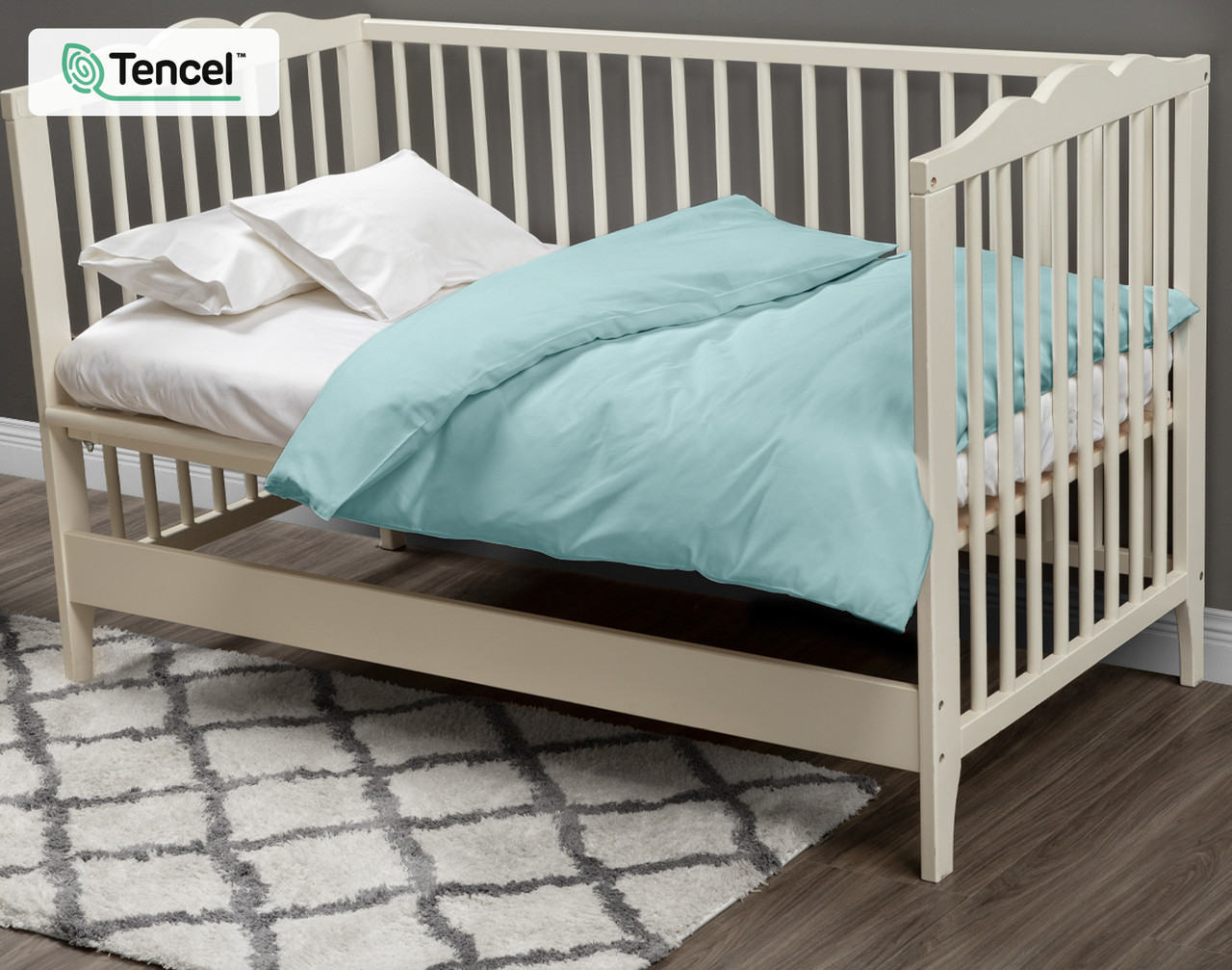 Our Eucalyptus Luxe Crib-Sized Duvet Cover in Shoreline dressed over a small white mattress in a cream white crib. 