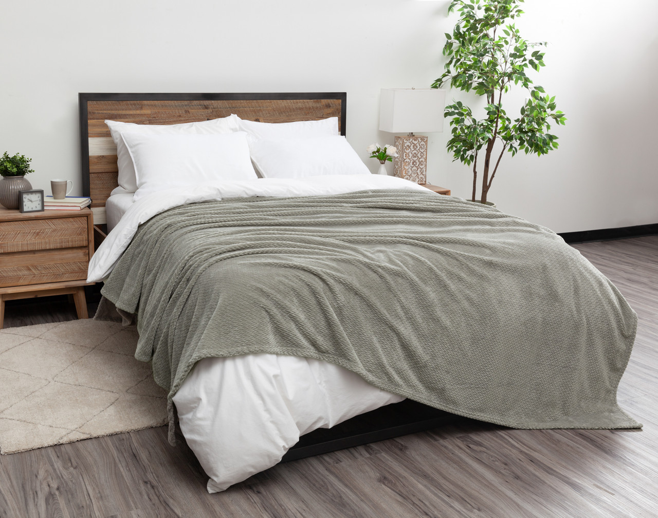 Angled view of our Grey Chevron Plush Blanket dressed over a white queen bed.