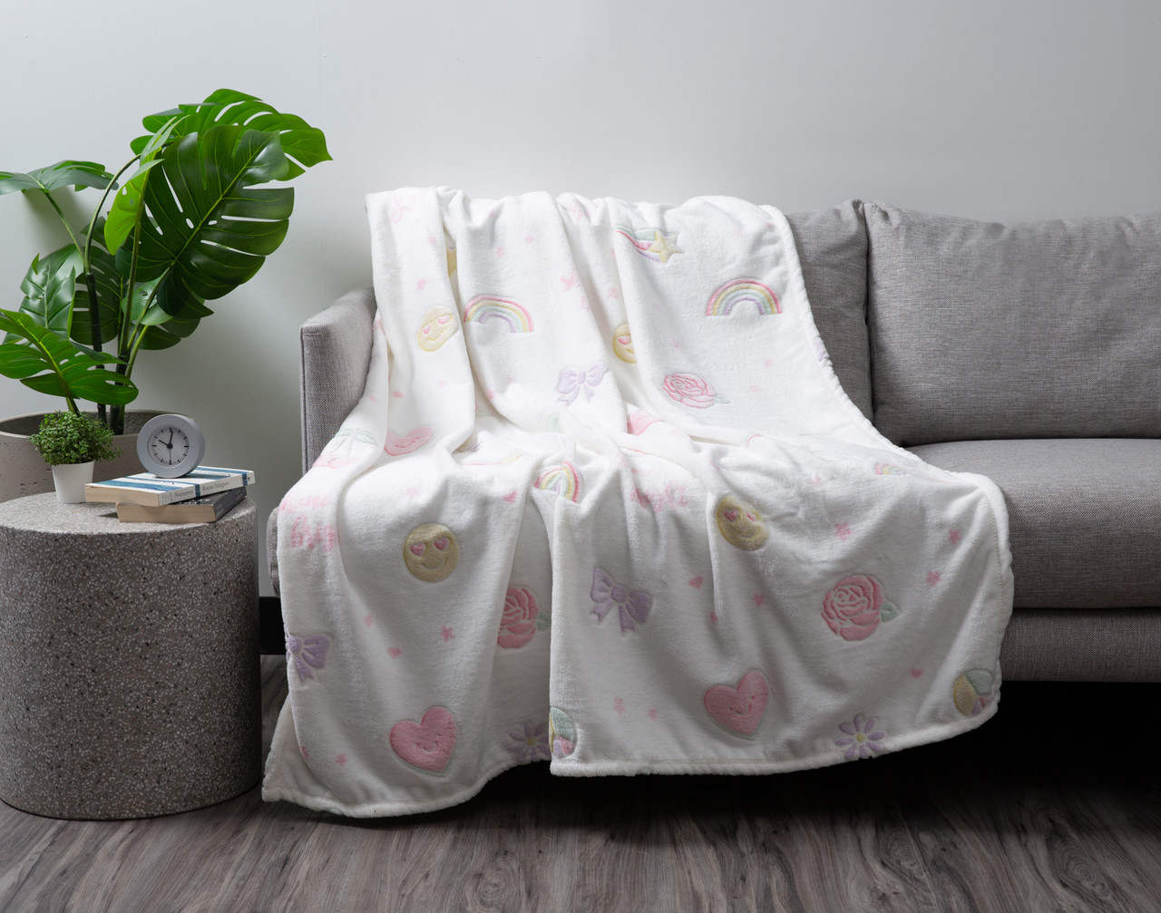 Our Peace & Love Glow in the Dark Fleece Throw draped over a grey couch in a modern living room.