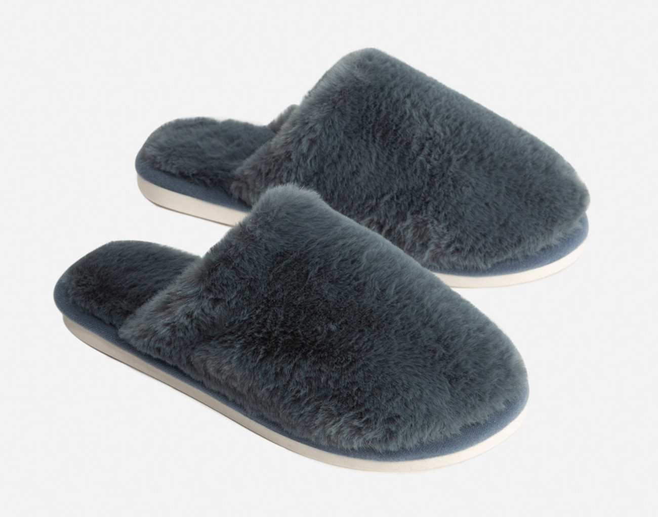 Side view of our Plush Faux Fur Grey Slippers in Thundercloud on a white floor.
