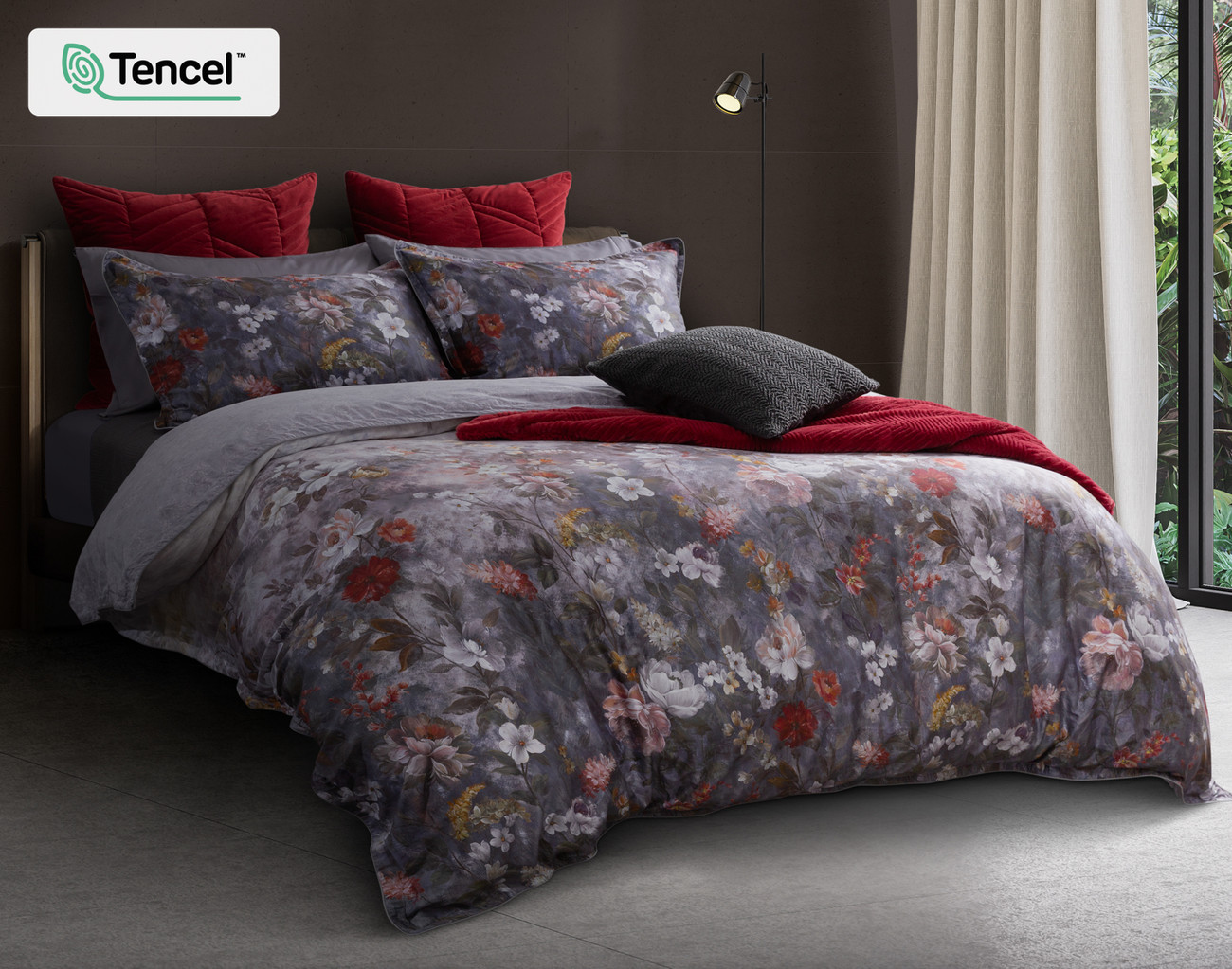 Vue en angle de notre housse de couette Renoir Floral sur un lit queen moderne avec des accessoires coordonnés rouges et gris.