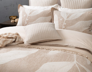 Angled view of our Natura Duvet Cover with cushions and throws draped overtop.