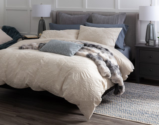 Angled view of our Marcona Duvet Cover Set dressing a queen bed with matching accessories in a simple bedroom.