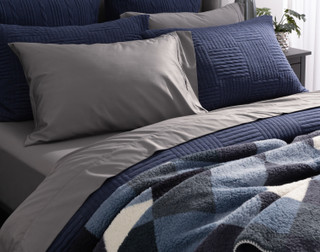 Closer angled side view of our Kye Duvet Cover Set dressing a queen bed with matching accessories and light grey sheets.