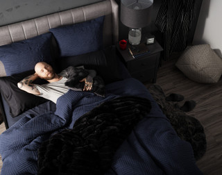 Top-down, angled view of a model lying in a bed dressed in our Kye Duvet Cover Set.