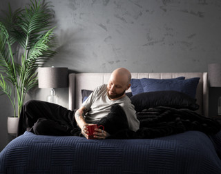 Front view of a model lying in a bed dressed in our Kye Duvet Cover Set.