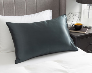 View of our Mulberry Silk Pillowcase in Thundercloud resting on a white bed with a grey headboard.
