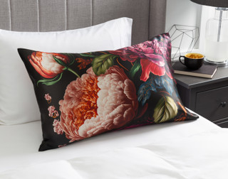 View of our Matilde Mulberry Silk Pillowcase resting on a white bed with a grey headboard.