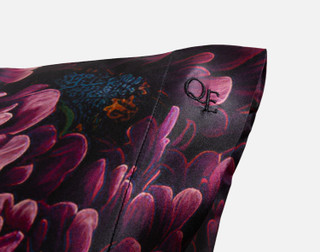 Close-up on the embroidered QE Home logo on the corner of our Matilde Mulberry Silk Pillowcase.