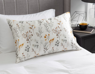 View of our Willow Mulberry Silk Pillowcase resting on a white bed with a grey headboard.
