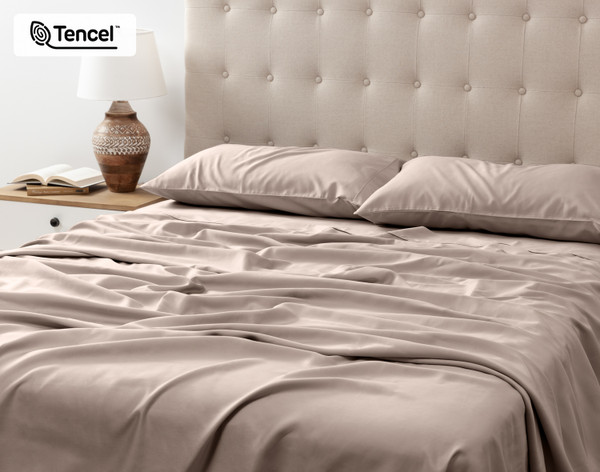 Angled view of our Eucalyptus Luxe TENCEL™ Lyocell Sheet Set in Ash Beige to show its flat sheet draped over the end of a queen bed.