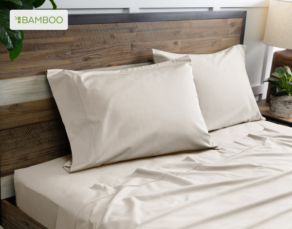 Two of our Bamboo Cotton Pillowcases in Driftwood Beige resting on a wooden bed with coordinating sheets.