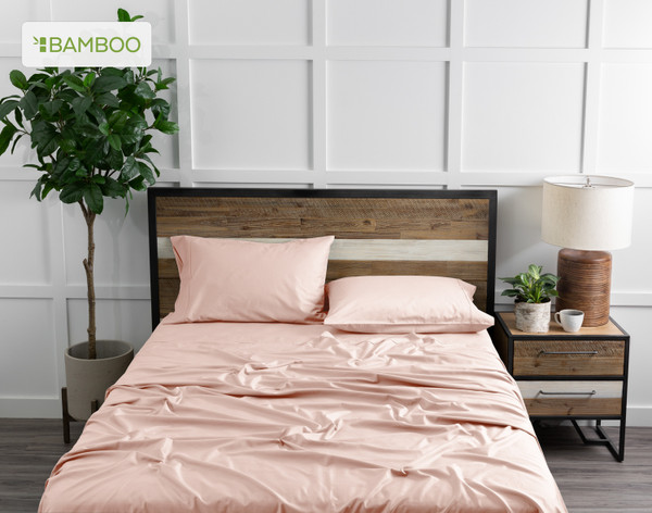 Vue de dessus de notre Bamboo Cotton drap  ensemble  in rose blush Pink habillé sur un lit en bois dans une chambre blanche remplie de plantes.